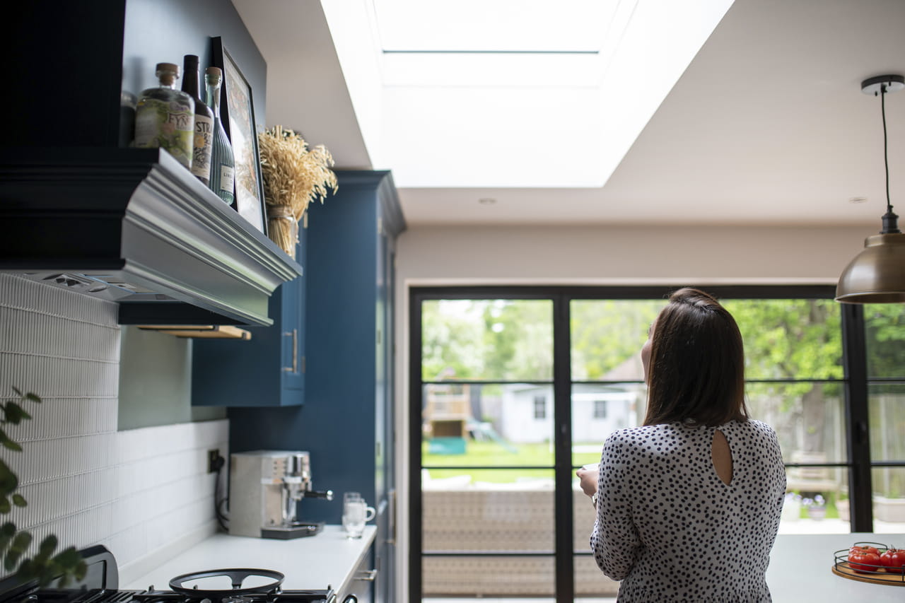 Woman in her kitchen looking up at her VELUX roof windows