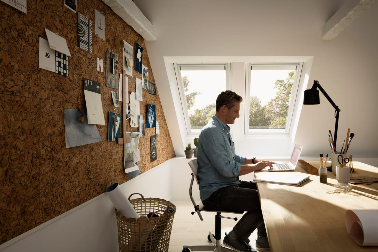 Woman sitting in her home office underneath VELUX 3-i-1 window