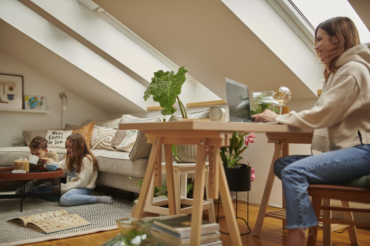 Woman sitting at her home office desk with light from VELUX roof windows