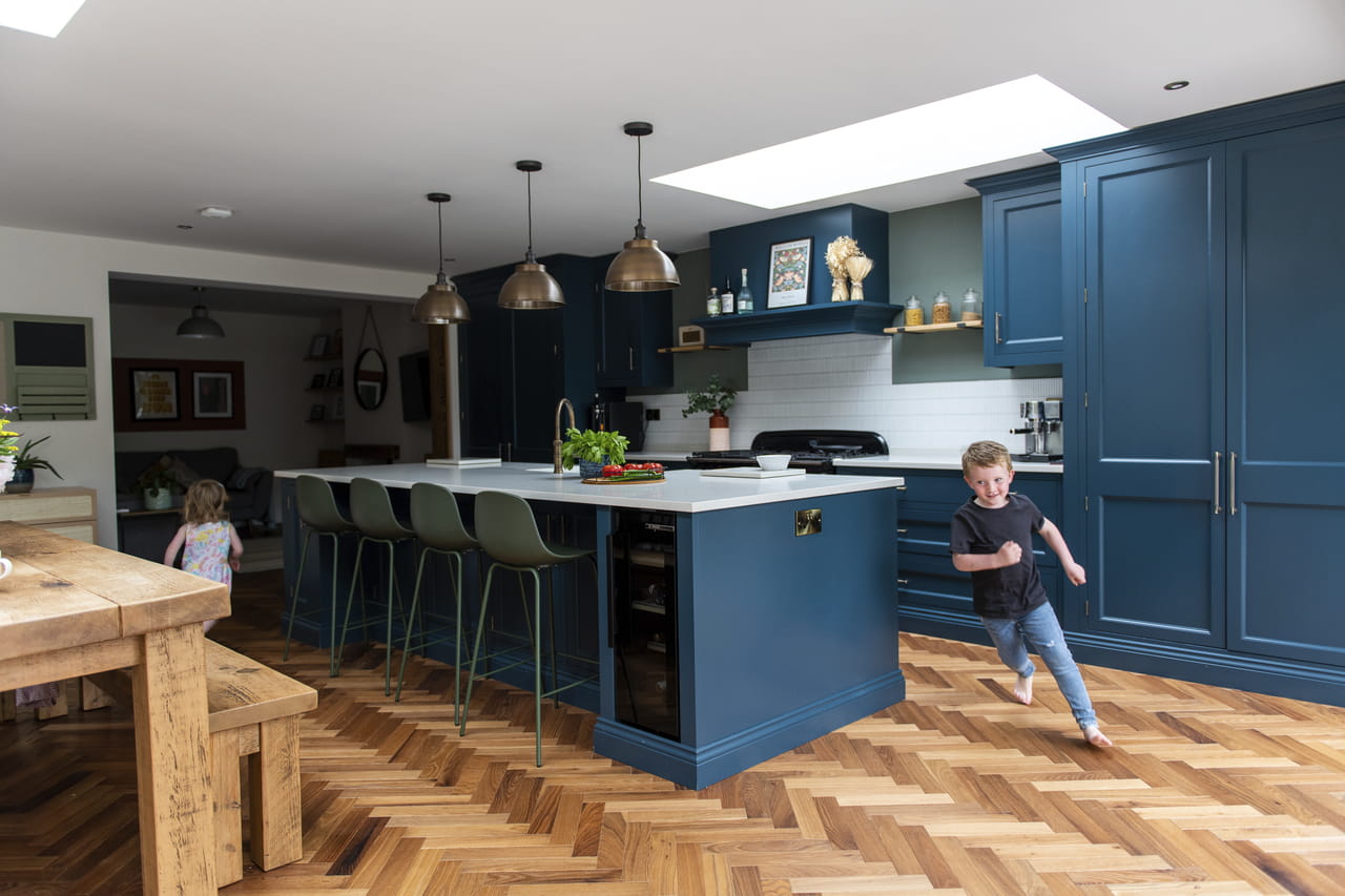 Boy running in kitchen filled with light from VELUX flat roof windows