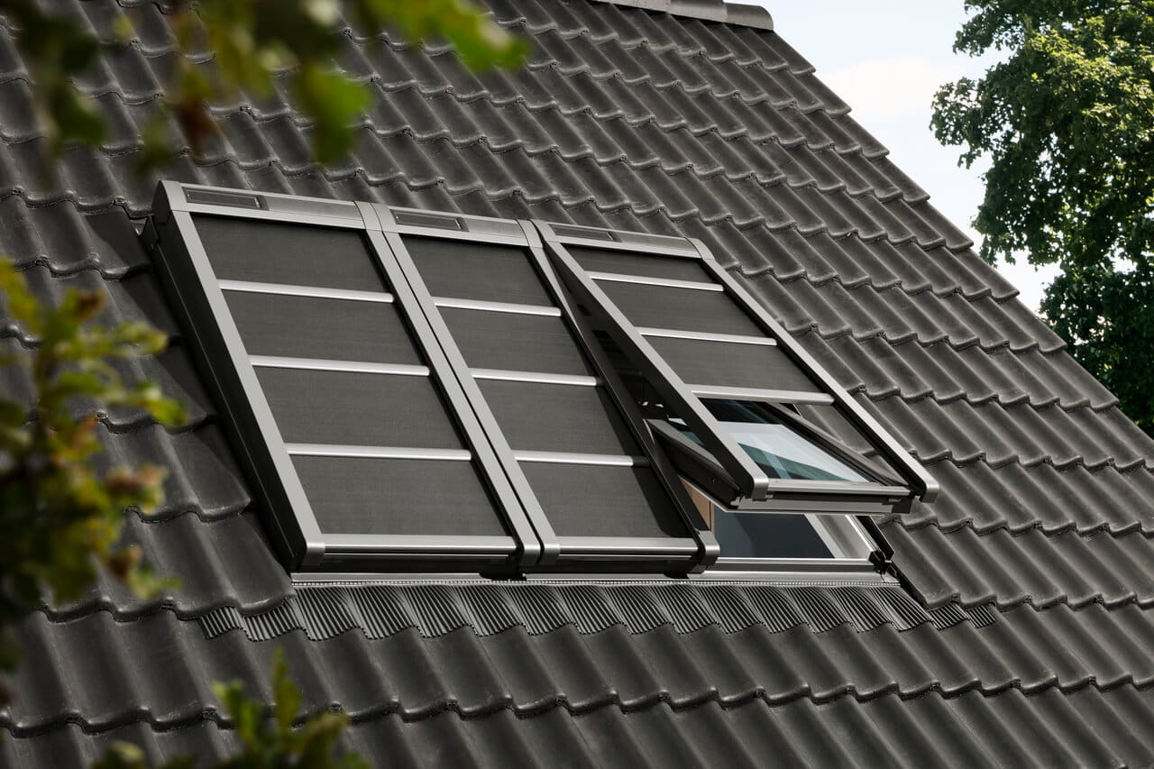 Exterior view of a roof with VELUX soft shutters, one partially opened.
