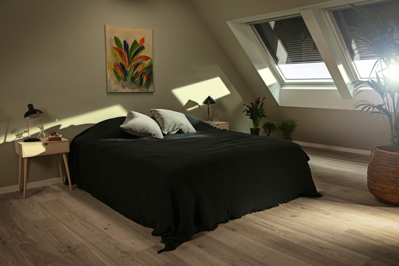 Bedroom with dark sheets and VELUX roller shutters in the window to block out heat and light