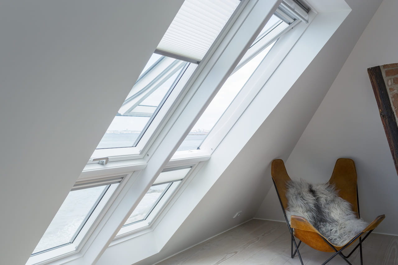 Două ferestre de acoperiș VELUX cu extensii înclinate și jaluzele plisate translucide instalate