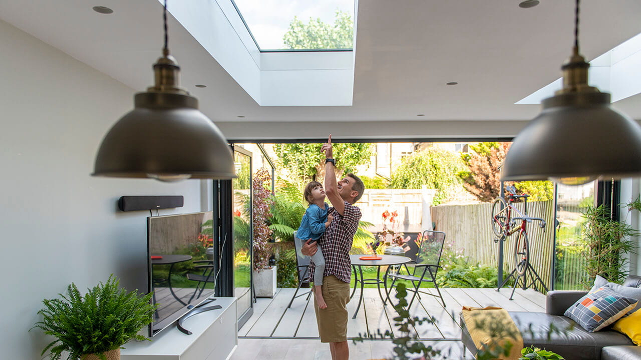 Parent and child in living room looking up at VELUX roof window.