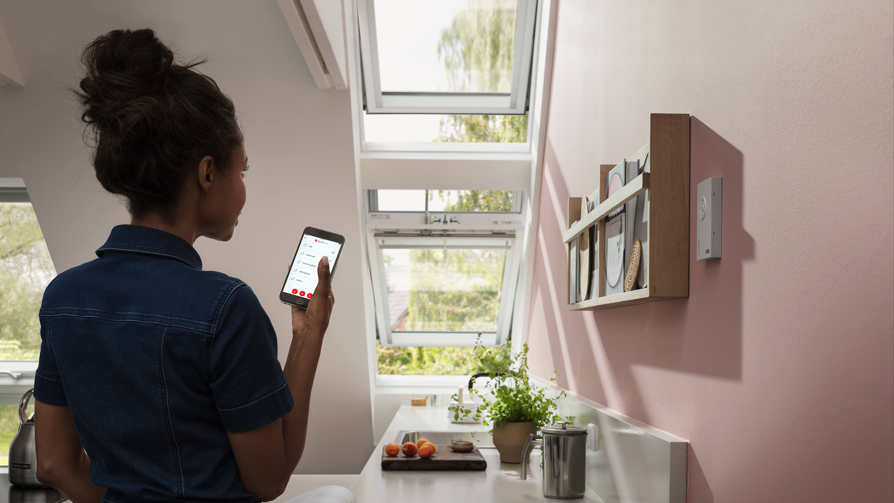 person holding smartphone and working with application to control electric remote controlled VELUX products